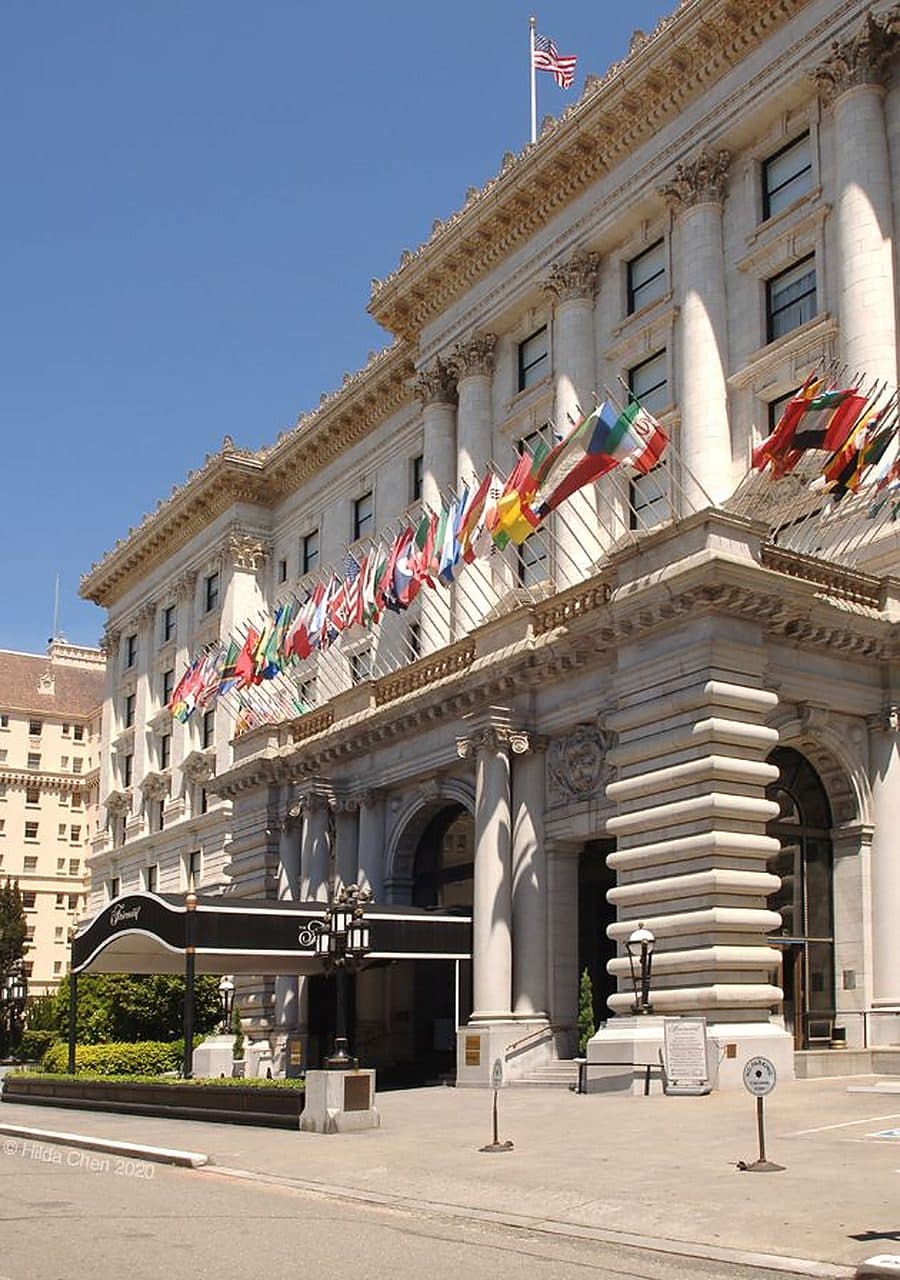 A grand San Francisco hotel facade lined with flags