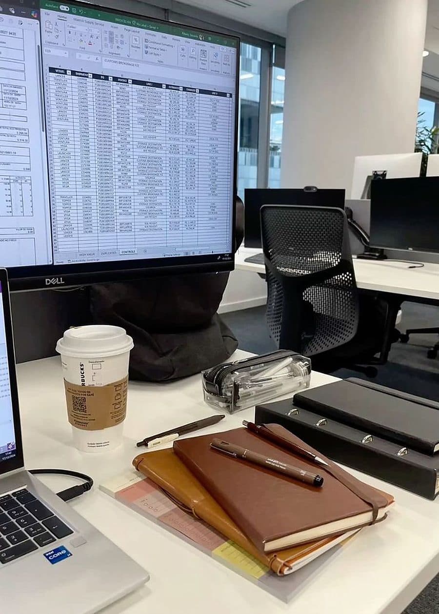 An office desk with notebooks, a coffee and a monitor