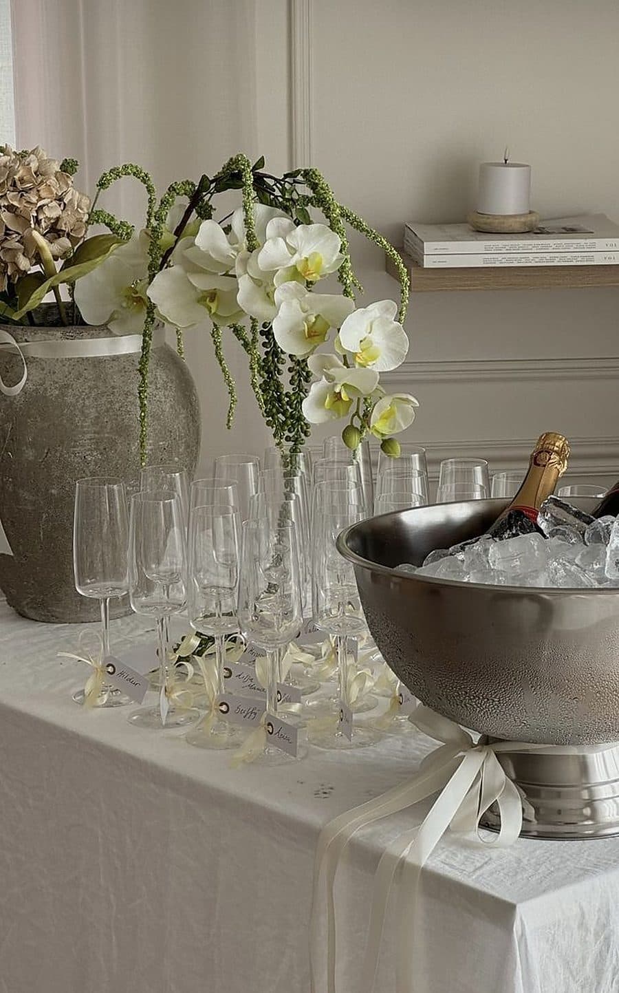 A styled table with orchids, champagne on ice and glasses set for a private gathering